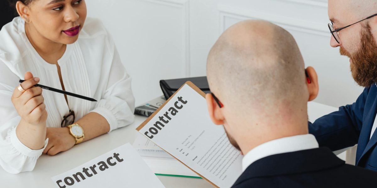 Business partners reviewing a detailed contract, discussing terms and conditions in a meeting.